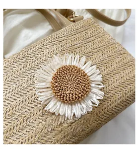 Close-up of woven straw bag with a large white daisy flower and brown PU leather straps