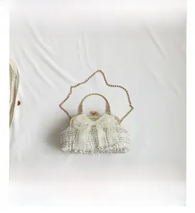 Detail of white woven shell bag with large mesh bow, pearls and metal chain strap