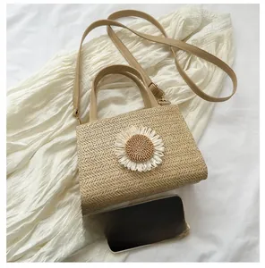 Detail of woven straw bag featuring a sunflower ornament and brown leather straps