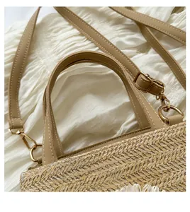 Detail of straw woven handbag featuring light khaki leather straps and golden metal buckles