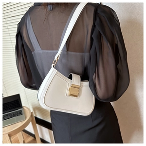 Détail du sac sous l'aisselle en cuir blanc avec une grande boucle dorée carrée chic