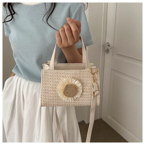 Detail of woven straw shoulder bag featuring a large sunflower and adjustable leather strap