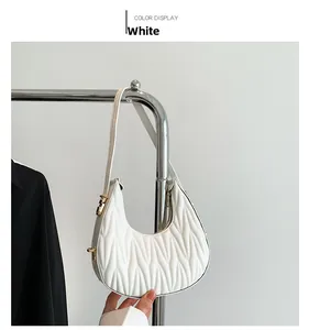 Detail of white crescent shoulder bag with V-shaped quilted pleats and metallic zipper