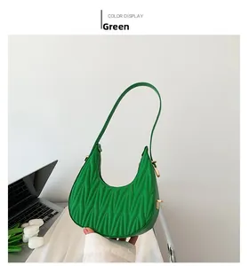 Detail of green matelassé crescent bag with gold hardware next to white tulips