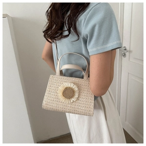 Detail of cream woven handbag with large sunflower decoration and leather handles