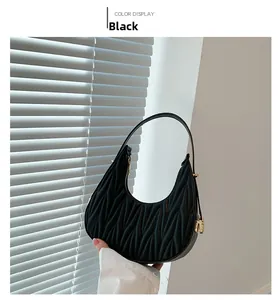 Close-up of black crescent underarm bag with quilted pleats and gold zipper detail
