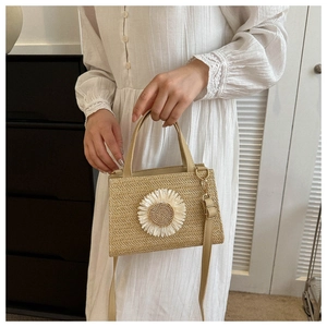 Detailed close-up of a beige straw handbag featuring 3D white daisy floral decorations