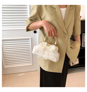 Detail van tweed handtas met mesh strik, parelmoer franje en goudkleurig handvat gedragen door model