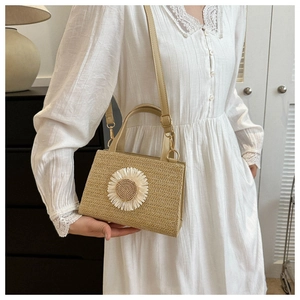Detail of straw woven crossbody bag featuring a white daisy flower on a summer purse