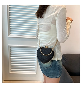Detail of heart-shaped black sequin crossbody bag with gold chain and metal handle