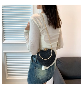 Detail of a black sequin heart-shaped crossbody bag with gold chain and handle