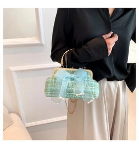 Detailopname van de mintgroene tweed handtas met blauwe tule strik en een parelhanger