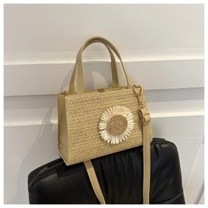 Detailed view of handmade woven straw tote bag with white daisy flower appliques