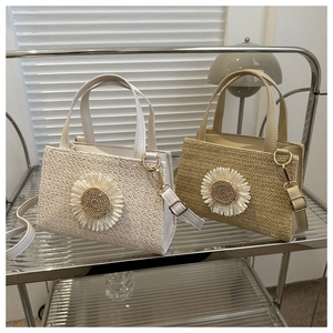 Detail of woven straw handbags in beige and khaki with large floral daisy appliques
