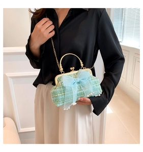 Detail of mint green tweed bag featuring a blue organza bow and pearl accents