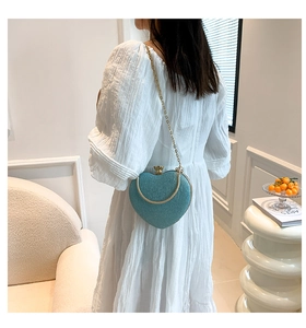 Woman carrying a heart-shaped glitter handbag in light blue with gold chain strap