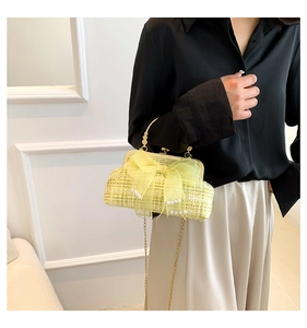 Detail of green tweed handbag featuring a large organza bow and white pearl accents