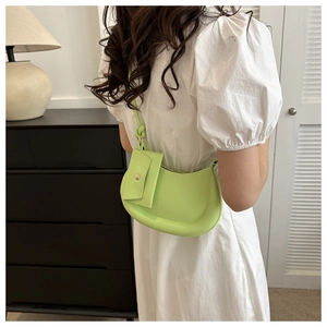 Detail of light green crescent underarm bag worn with white dress in casual setting