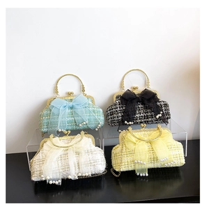 Close-up of four tweed evening bags with pearls and bows on a tiered display stand