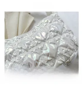 Close-up of white iridescent quilted shoulder bag with puff design and glossy finish