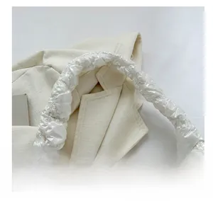 Detail of the soft pleated shoulder strap and silver quilted texture of the puff bag
