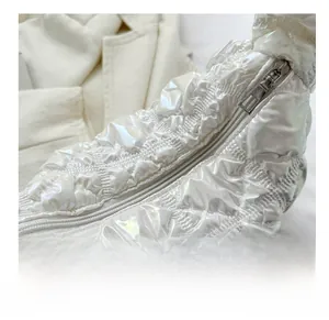 Detail shot of white pearlescent quilted handbag with silver zipper and puffy texture