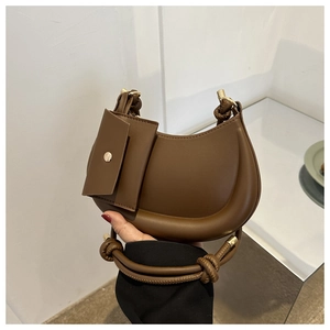 Detailed shot of brown crescent bag with a decorative pouch and twisted rope handle