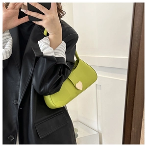 Mirror selfie showing a lime green baguette bag with a large golden heart metal buckle