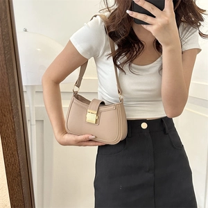Sac baguette rétro marron clair avec fermoir doré porté par un mannequin en tenue chic