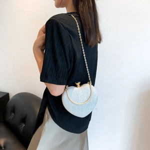 Silver glitter heart-shaped evening bag with gold chain strap shown on model shoulder