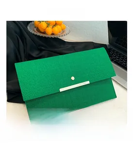 Vue détaillée de la pochette vert néon à texture crocodile avec garniture dorée sur table blanche
