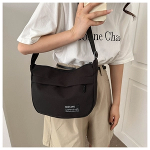 Nylon dumpling bag worn as a crossbody showing product size and adjustable strap