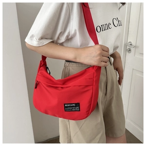 Close-up of a red nylon crescent crossbody bag with branded label and wide shoulder strap