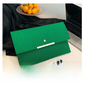 Pochette enveloppe verte à motif crocodile à côté d'un smartphone montrant la taille