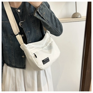 Detail of white minimalist nylon crossbody bag with adjustable wide cream shoulder strap