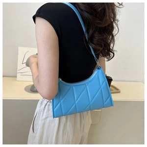 Sky blue quilted baguette bag with rectangular design worn by a model in a minimal setting