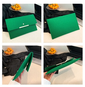 Détails d'une pochette enveloppe vert vif avec texture crocodile et boucle dorée