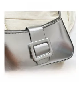 Detail of silver metallic shoulder bag showing large square buckle and mirror finish texture