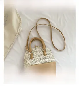 Detail shot of straw handbag featuring floral embroidery and brown leather straps