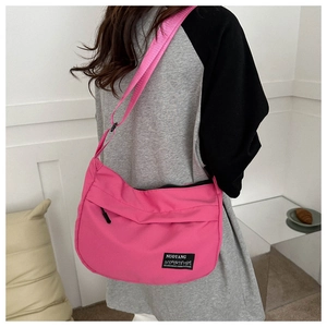 Detail of rose pink nylon crossbody bag with adjustable wide strap and brand label