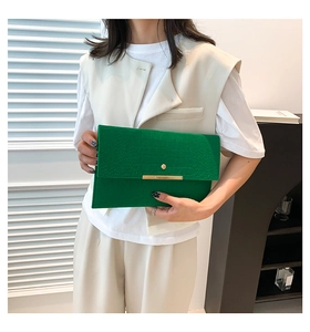 Détail de la pochette enveloppe verte en cuir croco avec barre dorée et boucle chic