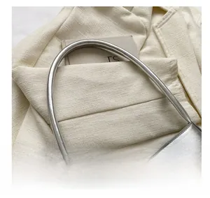Detail of silver metallic handbag with square buckle and sleek shoulder strap on tweed fabric