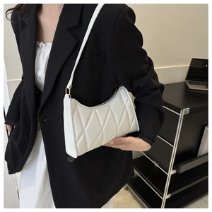 Close-up of white quilted leather underarm bag with elegant diamond stitching and gold hardware
