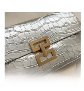 Detail of silver stone pattern clutch with a glossy finish and golden interlocking buckle