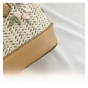 Detailed close-up of straw woven texture with floral embroidery and PU leather piping
