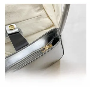 Detail view of smooth golden zipper and magnetic buckle on silver shoulder bag