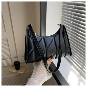 Detail of black quilted shoulder bag featuring geometric patterns and golden zipper