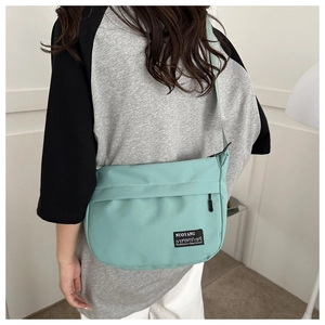 Detail of mint green crossbody bag with adjustable wide strap and logo patch
