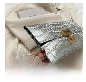 Detailed view of silver crocodile pattern clutch bag featuring luxury gold metallic lock