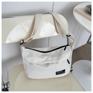 Detail of white nylon crossbody bag with zipper closure and logo tag on a white chair